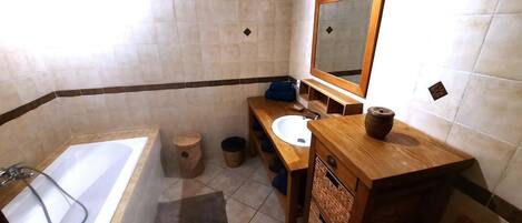 A bathroom with a bathtub, sink, mirror, and wooden vanity.