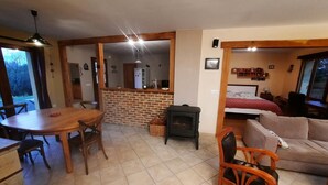 Una sala de estar acogedora con chimenea, un comedor con mesa y sillas de madera, y una kitchenette con pared de ladrillo.
