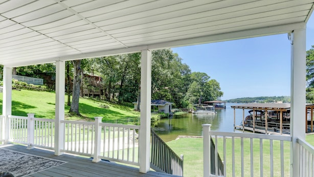 A covered deck with white railings overlooking a lake with boats and a dock. - Waterfront Lake Hamilton Getaway w/ Boat Ramp! (Hot Springs)
