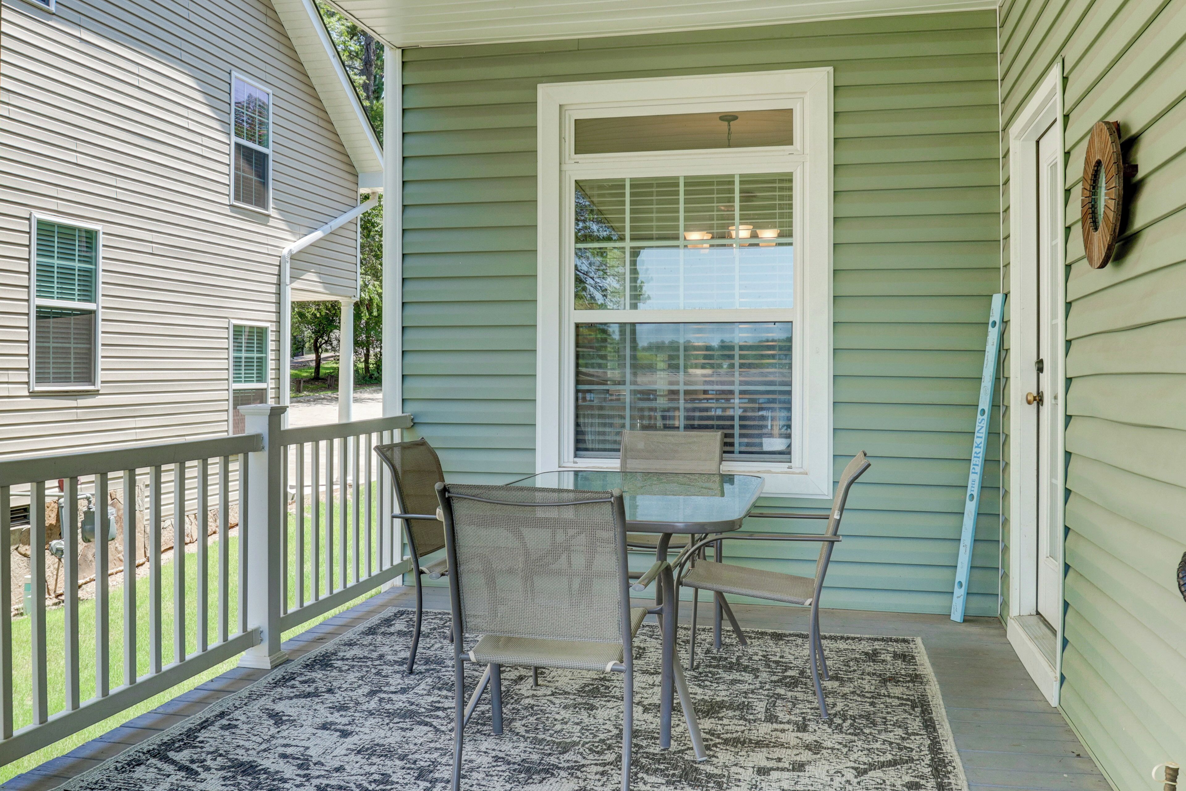 A porch with a table and chairs, a railing, and a window.