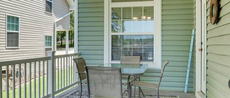 A porch with a table and chairs, a railing, and a window.