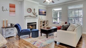 A living room with a fireplace, a ceiling fan, and a large window with blinds. - Waterfront Lake Hamilton Getaway w/ Boat Ramp! (Hot Springs)