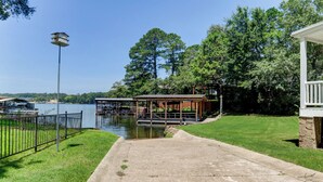 A lakeside walkway leading to a dock area with a gazebo, a lamp post, and a stone building. - Waterfront Lake Hamilton Getaway w/ Boat Ramp! (Hot Springs)