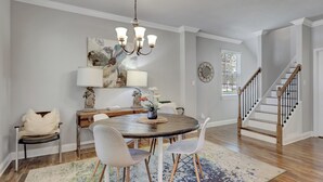 A dining area with a round table, chairs, a chandelier, and a staircase. - Waterfront Lake Hamilton Getaway w/ Boat Ramp! (Hot Springs)