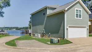 A two-story house with a garage, a lawn, and a dock by a lake. - Waterfront Lake Hamilton Getaway w/ Boat Ramp! (Hot Springs)