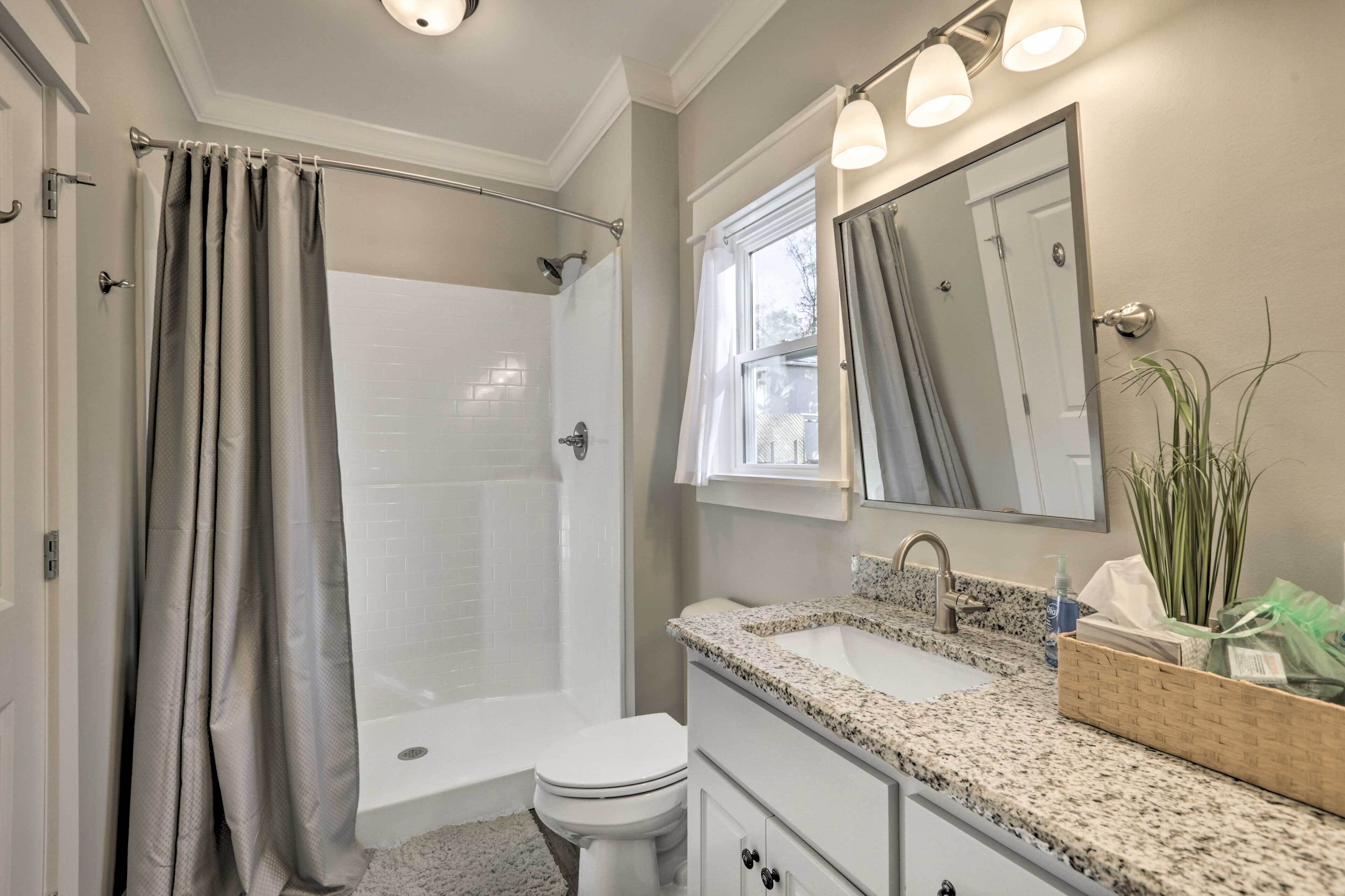 A bathroom with a shower, toilet, sink, and vanity.