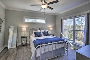 A bedroom with a bed, two bedside tables, a ceiling fan, a window, and a view of trees. - White Oak Creek Home w/ Views, Deck & Pool Access! (Eufaula)