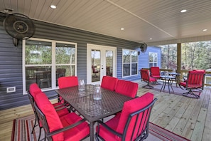 A covered patio with a table and chairs, large windows, and a fan. - White Oak Creek Home w/ Views, Deck & Pool Access! (Eufaula)