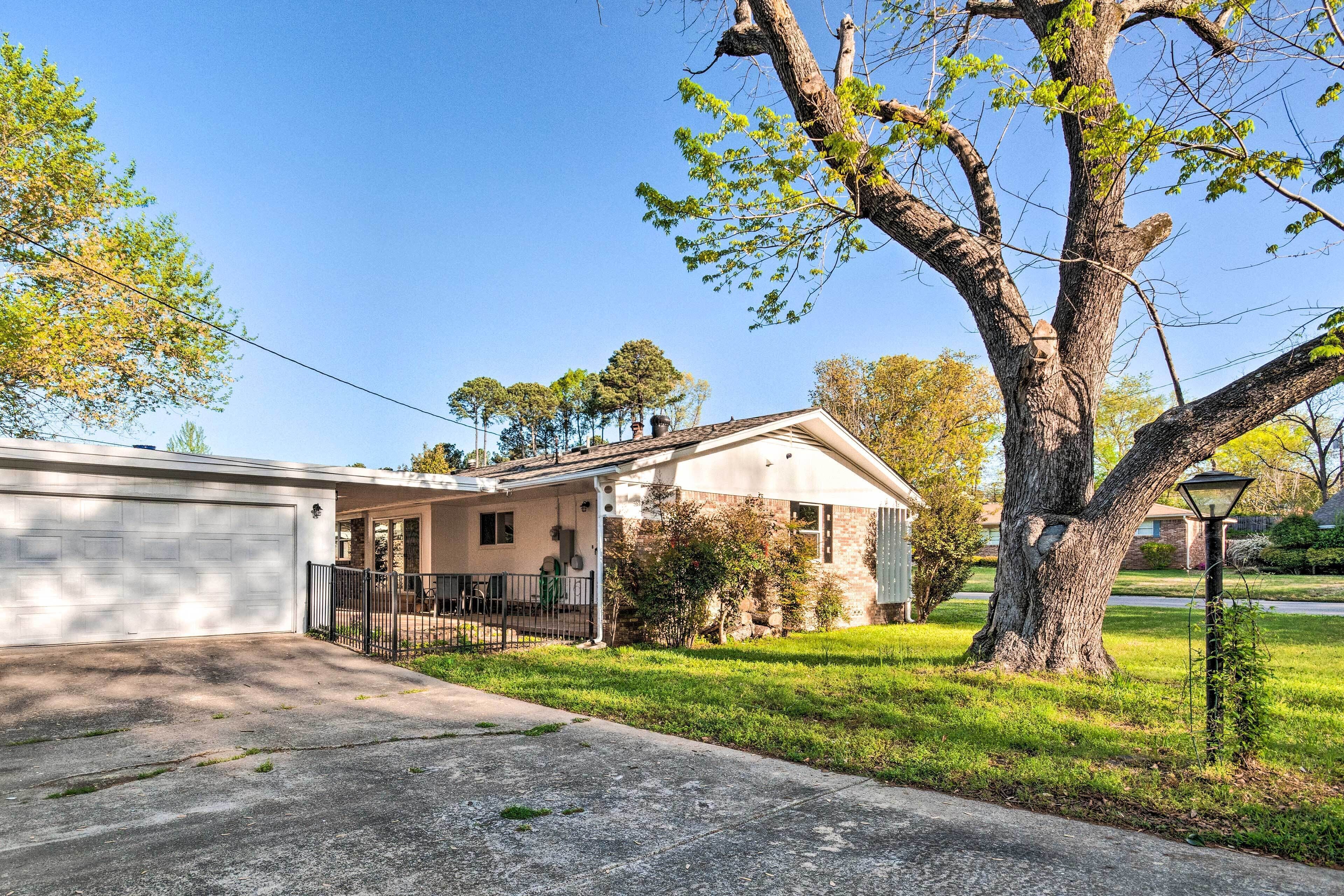 A single-story house with a garage, a covered porch, and a large tree in front.