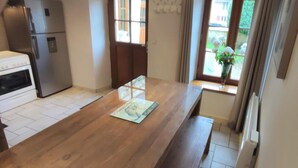 Eine Küche mit einem Holztisch, einem Kühlschrank und einem Fenster mit Blick auf Grünflächen.