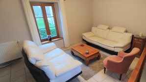 Ein Wohnzimmer mit einem weißen Sofa, einem rosafarbenen Sessel, einem Holztisch und einem kleinen Beistelltisch.