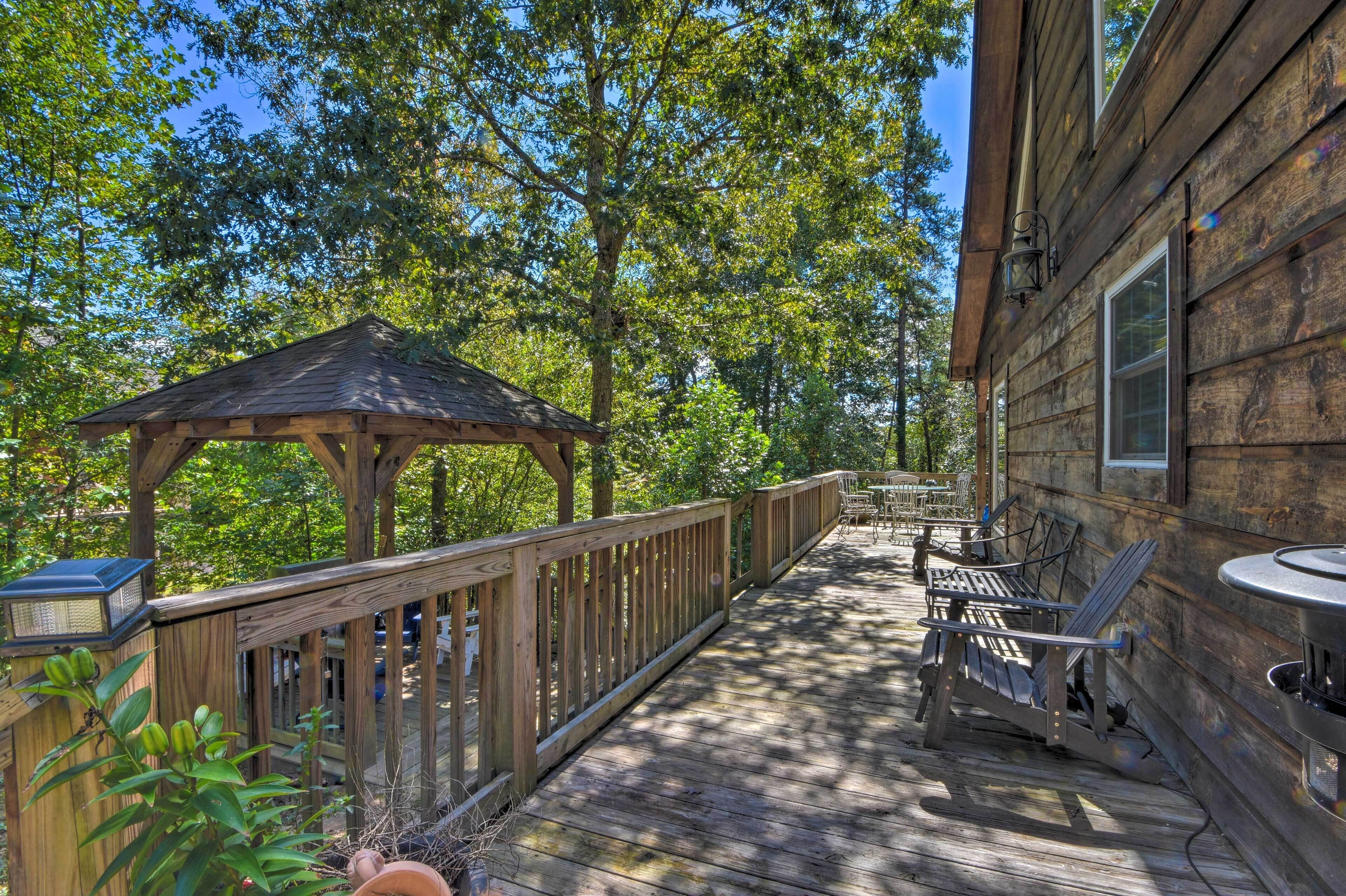 A wooden deck with a gazebo, outdoor seating, and a barbecue area.