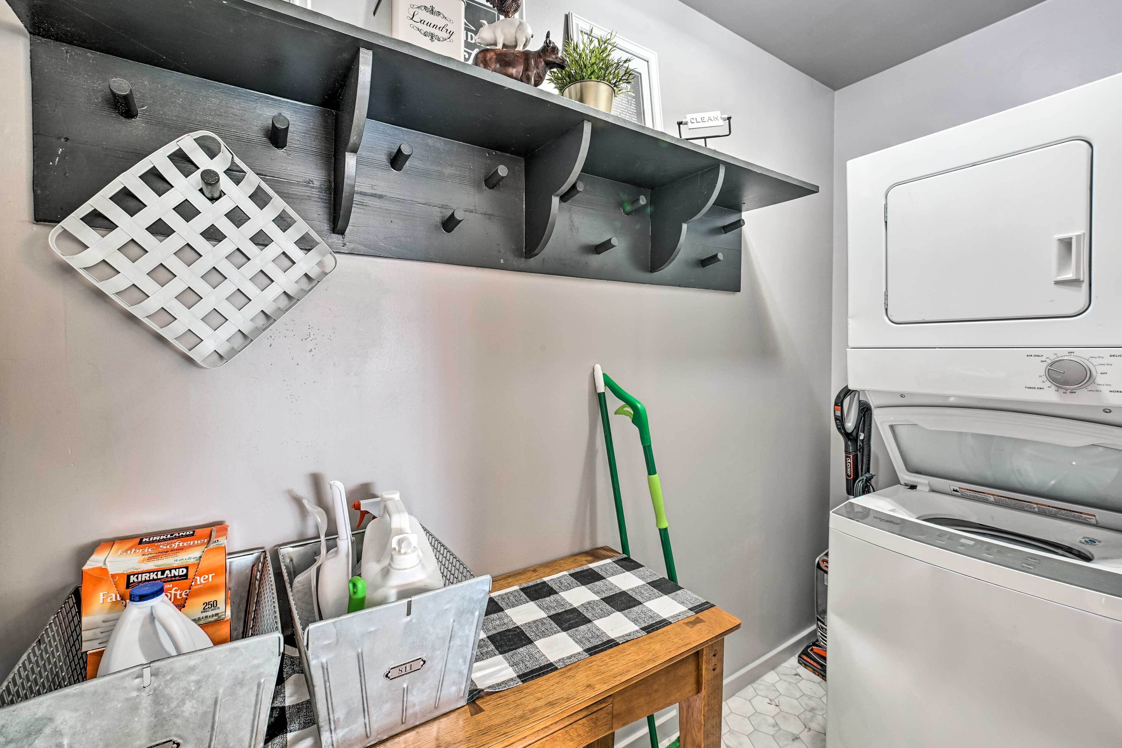 Een keuken met een inbouwoven, een metalen droogrek, een houten tafel met een geruit tafelonderzetter en een groene dweil.