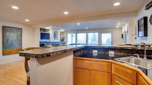 A modern kitchen with a granite countertop, wooden cabinets, and a stainless steel sink. - Grand Junction Abode ~ 2 Miles to Wineries & Golf! (Grand Junction)