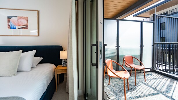 Un dormitorio con cama, mesita de noche, lámpara y un ventanal grande.