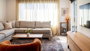 Una sala de estar moderna con un sofá modular, una mesa de centro con flores, una mesita auxiliar y un mueble.