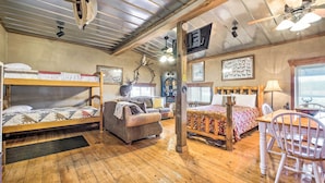A rustic cabin-style room with bunk beds, a sofa, a dining table, and a ceiling fan. - Renovated Bunkhouse on 12-acre Horse Farm! (Perrysville)