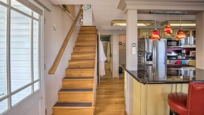 A staircase leading to a second floor, a kitchen area with a refrigerator, and a dining area with a chair.
