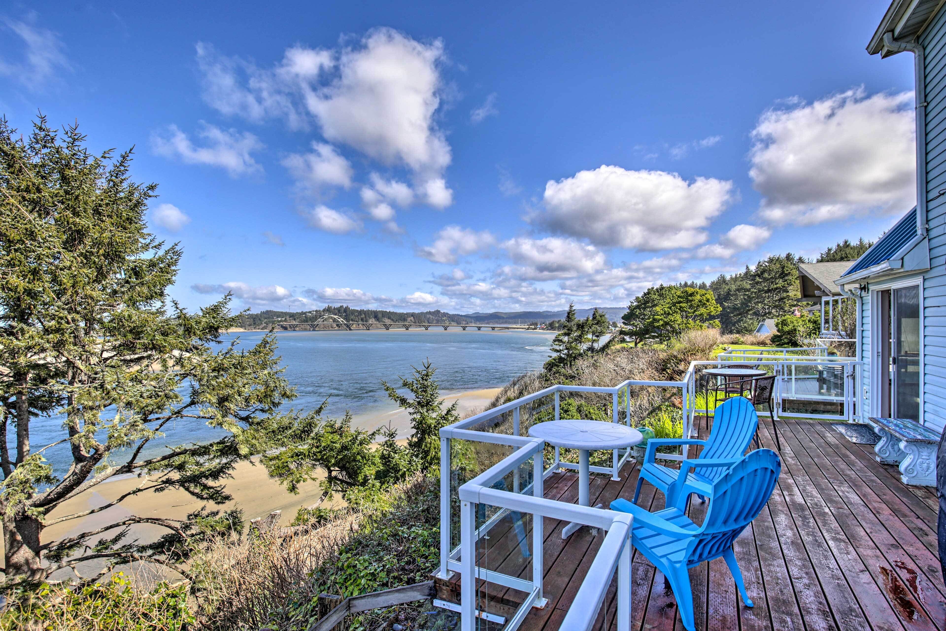 A deck with blue chairs overlooking a lake, a wooden deck, and a house with a blue exterior.