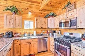 Cocina estilo cabaña de madera con encimeras de granito, electrodomésticos de acero inoxidable y armarios de madera.