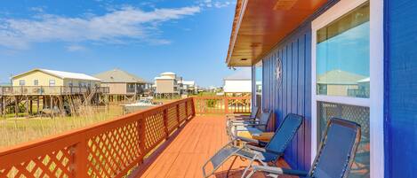 A wooden deck with lounge chairs and a view of houses in the background.