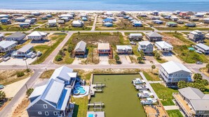 An aerial view of a coastal residential area with houses, a marina, and a beach. - Breezy Dauphin Island Vacation Rental With Deck! (Dauphin Island)