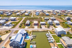 Luchtbeeld van een kustgebied met woningen, een jachthaven en een strand op de achtergrond.