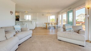 A spacious living room with two sofas, a dining table, and a kitchen in the background. - Breezy Dauphin Island Vacation Rental With Deck! (Dauphin Island)