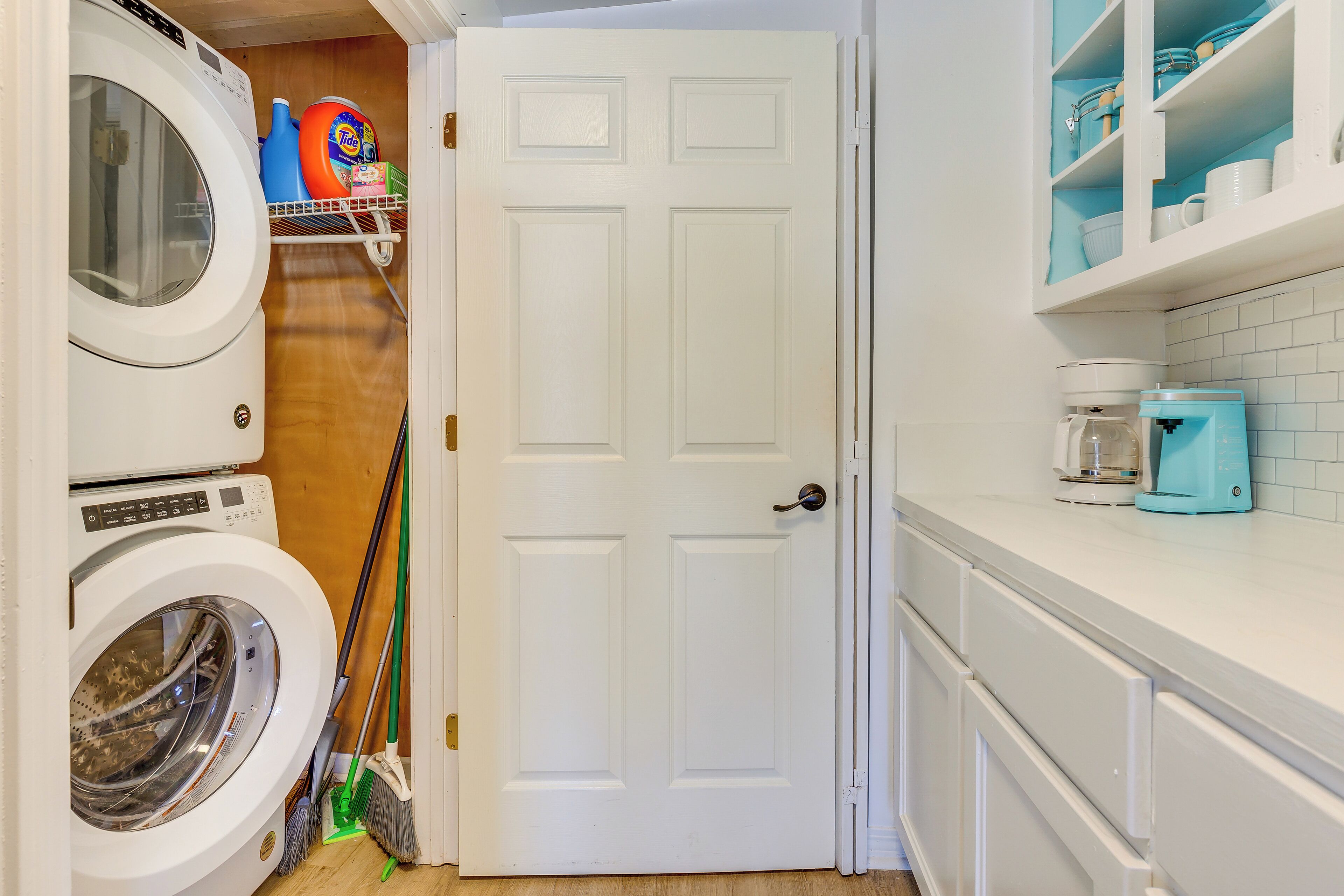 A laundry area with a washing machine, a broom, and cleaning supplies.