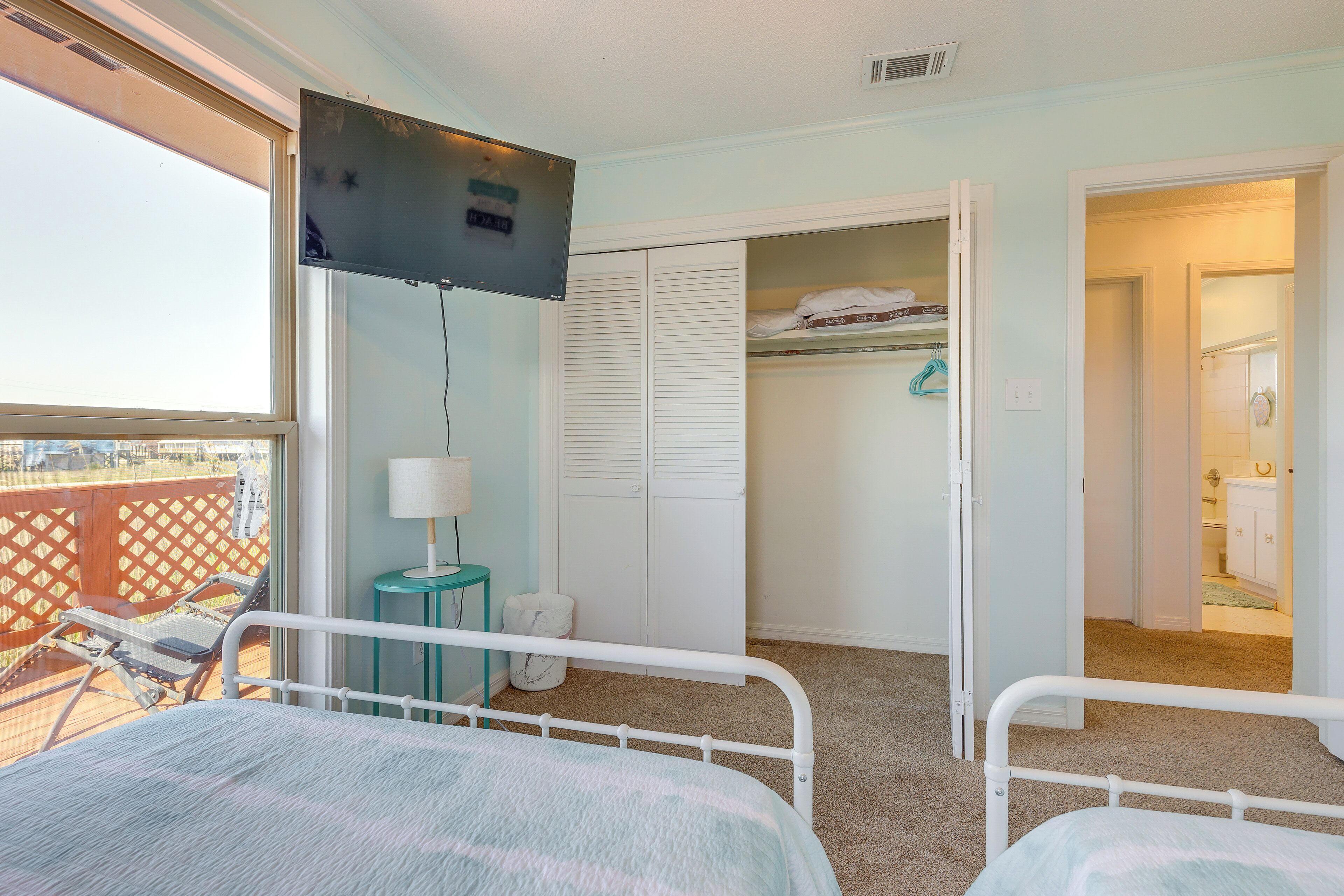 A hotel room with a bed, a TV, a closet, and a balcony.