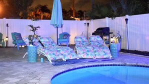 Un espace aménagé au bord de la piscine, avec des chaises longues et un barbecue.