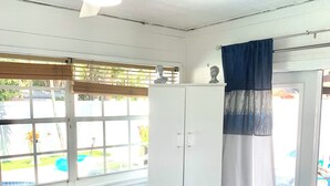 Une chambre avec un lit, une armoire, un ventilateur de plafond et une fenêtre donnant sur l’extérieur.