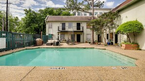 A swimming pool with a 4-foot depth, a covered patio area, and a building with a balcony in the background. - Contemporary Dallas Condo w/ Pool Access! (Dallas)