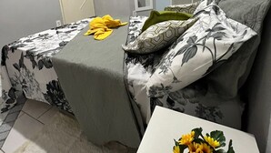 Un dormitorio con una cama, una mesita de noche con un florero, un armario y un espejo.