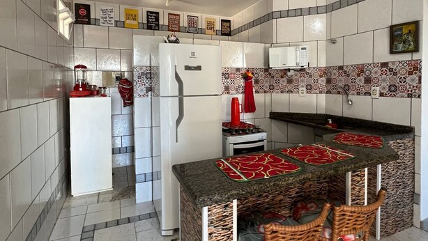 Una cocina moderna con armarios blancos, una isla central con taburetes altos, un refrigerador y un microondas.
