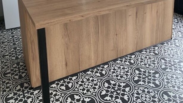 Uma cozinha moderna com ilha central, eletrodomésticos de aço inoxidável e piso estampado.