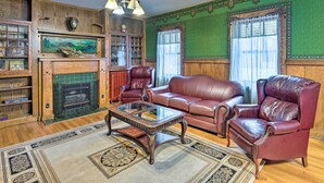 Ein traditionell eingerichtetes Wohnzimmer mit Kamin, Ledersofas, einem Glastisch und einem Bücherregal aus Holz.