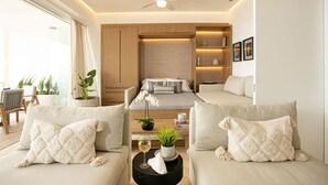 A modern living room with a sofa set, a coffee table with a glass of wine, a ceiling fan, and a bookshelf.