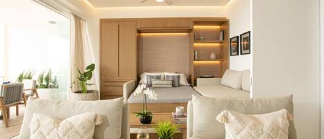 A modern living room with a sofa set, a coffee table with a glass of wine, a ceiling fan, and a bookshelf.