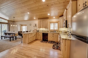 Una cocina amplia con armarios de madera, un refrigerador grande y un comedor con mesa y sillas.