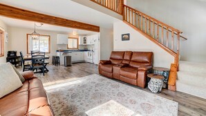 A spacious living area with a leather sofa, a dining table, and a kitchen in the background. - Roscommon Retreat w/ Deck ~ 1 Mile to Higgins Lake (Roscommon)