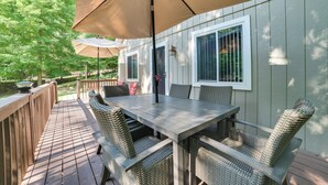 An outdoor deck with a wooden table and wicker chairs, surrounded by a wooden railing. - Roscommon Retreat w/ Deck ~ 1 Mile to Higgins Lake (Roscommon)