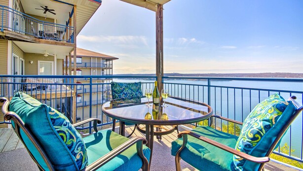 A balcony with a table and chairs, overlooking a body of water.