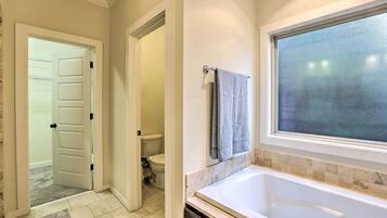 A bathroom with a bathtub, a toilet, and a shower area.