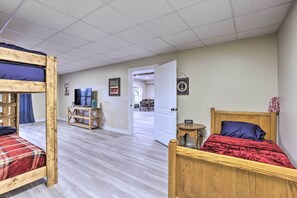 Una habitación con literas, televisión, una mesita y una puerta que da a otra habitación.