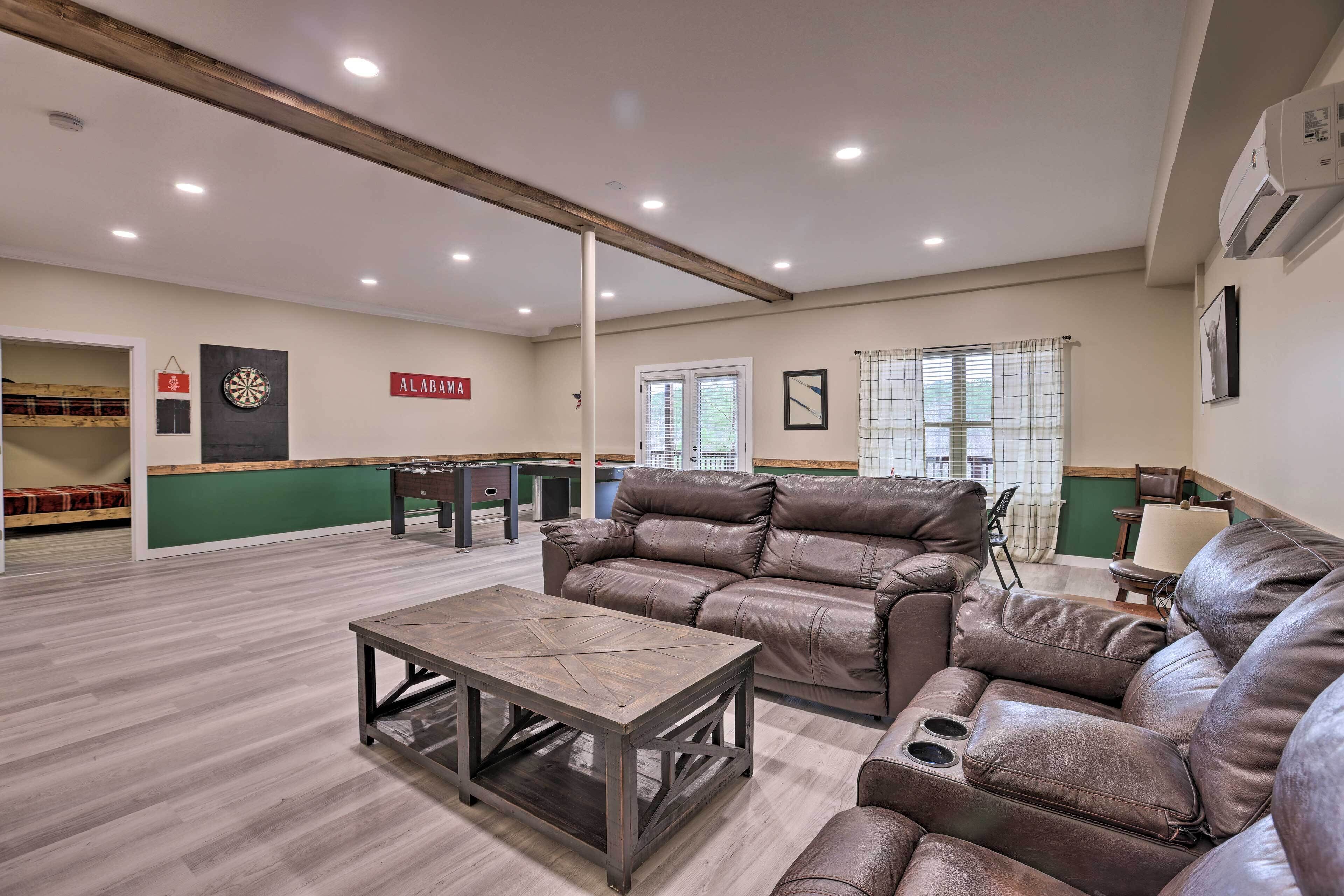 A spacious living area with a leather sofa, a wooden coffee table, and a dartboard.