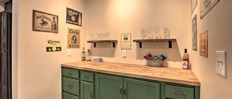 A kitchen with green cabinets, a wooden countertop, and various branded items like Corona beer and Miller Brewing Company.