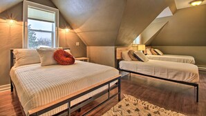 A bedroom with a sloped ceiling, two beds, a window with blinds, and wall-mounted lights. - Ely Getaway Near Town, Lakes, & Outdoor Recreation (Ely)