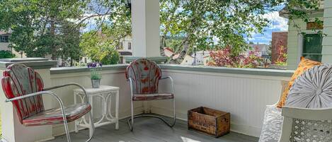 A porch with two rocking chairs, a small table, and a wooden crate.