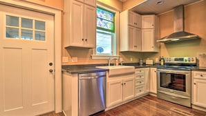 A kitchen with white cabinets, a dishwasher, a stainless steel oven, and a window with stained glass. - Ely Getaway Near Town, Lakes, & Outdoor Recreation (Ely)
